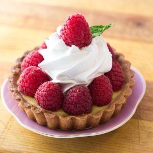 Strawberry Lemon Tart with Whipped Cream sitting on a pink plate resting on wooden table